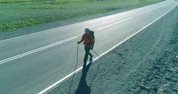 飞越搭车游客走在沥青路上巨大的乡村山谷在