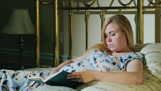 怀孕的女人在床上看书