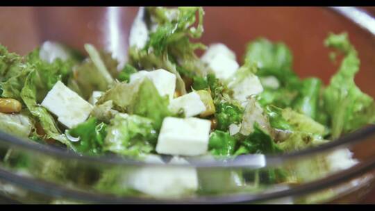 慢动作特写镜头，用叉子混合新鲜沙拉。