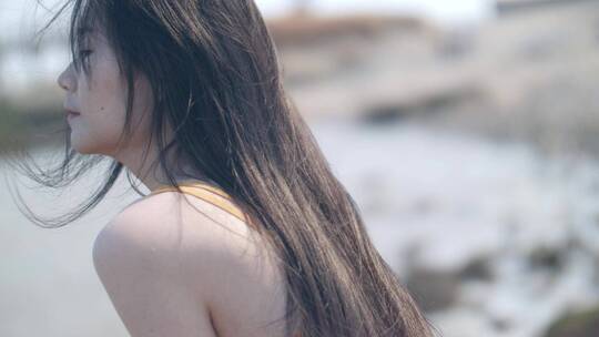 女孩坐在海边吹风，感受自然