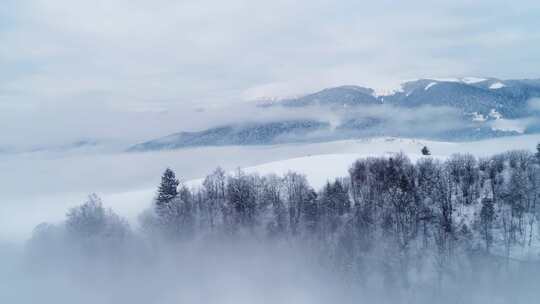 飞越冬季雾蒙蒙的雪山鸟瞰美丽的冬日风景