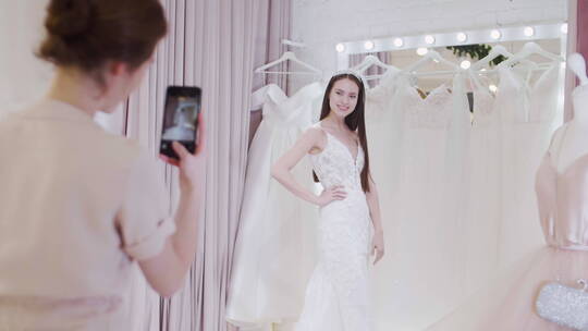 女人在为试穿婚纱的新娘拍照