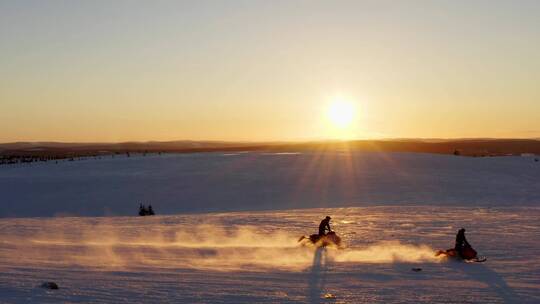 日落时骑着摩托雪橇穿过雪地