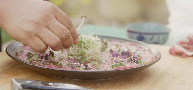 厨师艺术地将蘑菇放在装有香料的肉盘中