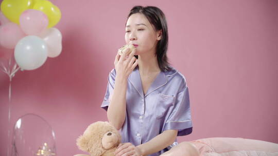 坐在床上吃甜甜圈的年轻女孩
