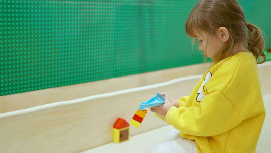 学龄前女孩玩积木专注于将积木连接到她的创