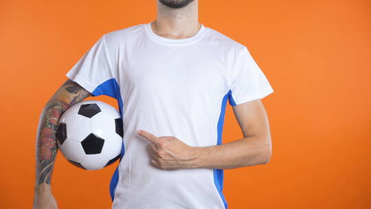 足球运动员用手指指着足球衫上的隐形标志