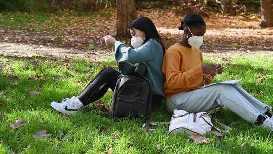 女人背靠背坐在草地上