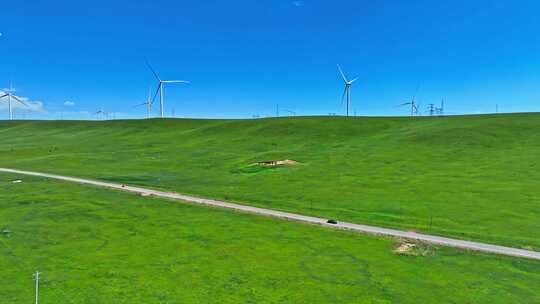 新能源汽车行驶在祁连山草原风力发电场