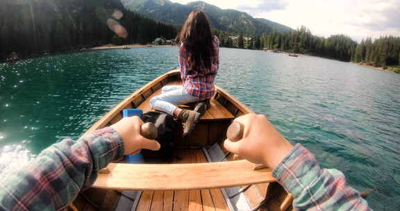 一个男人划着木船在湖中央划船，看着他的妻