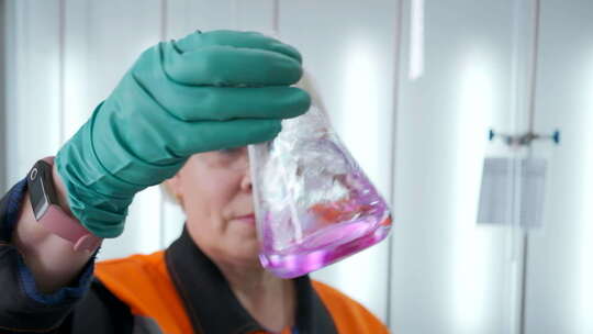 化学家拿着装有化学液体的烧瓶。夹子。化学视频素材模板下载