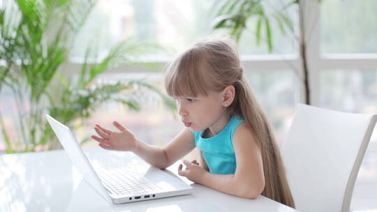小女孩在桌子上用笔记本电脑