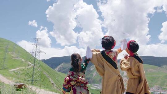 三个藏族儿童在山顶放飞纸飞机
