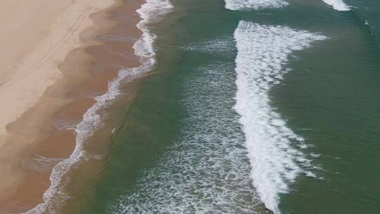 航拍海岸边的海浪冲向沙滩