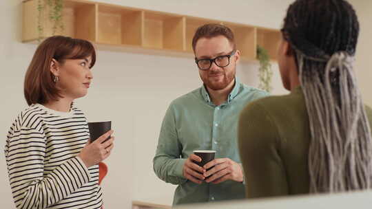三个友好的多民族同事站在办公室里喝咖啡，视频素材模板下载