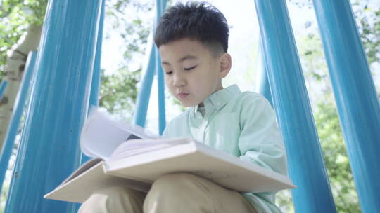 小男孩坐在户外看书视频素材模板下载
