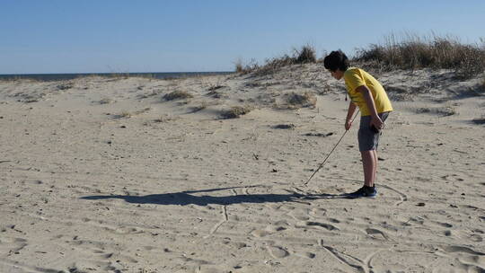 小男孩在沙滩上用树枝画画视频素材模板下载