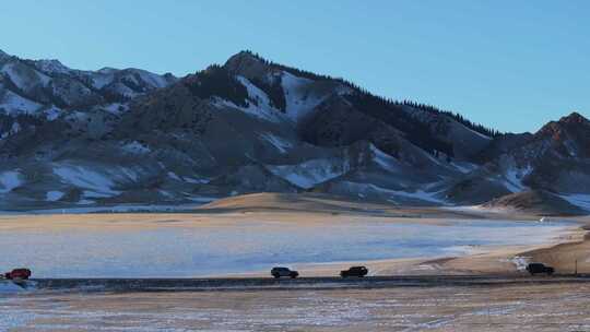 航拍冬季新疆赛里木湖雪山环湖公路夕阳车辆