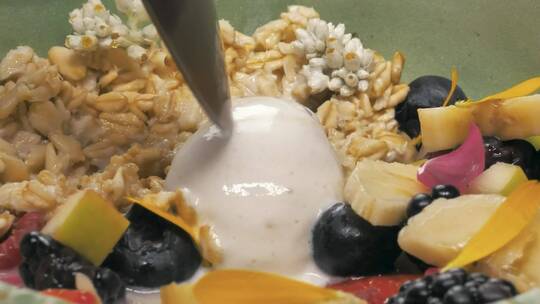 用勺子舀着酸奶和时令水果的混合物