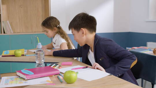 男学生从同学的桌子上拿起一支铅笔视频素材模板下载