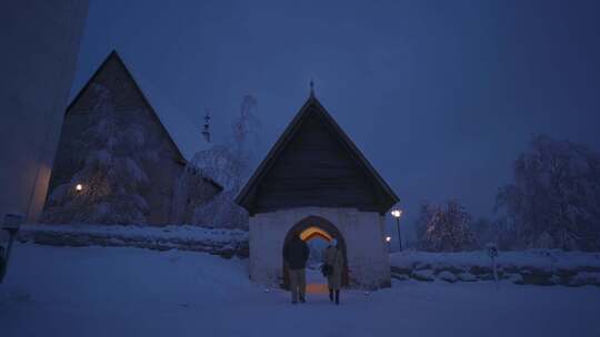 一男一女晚上在雪地里走在拱形建筑下