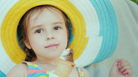 一个戴着帽子的小女孩吃冰淇淋