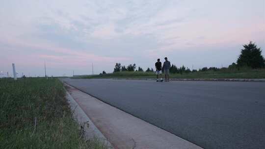 男性滑板手和朋友在美国空旷的道路上检查电