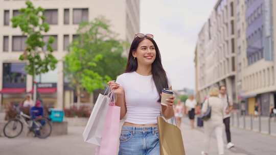 混血女人拿着购物袋，在城市户外散步时喝酒