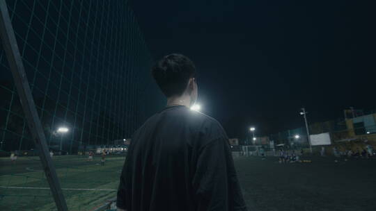 夜晚一个人站在足球场上看向前方