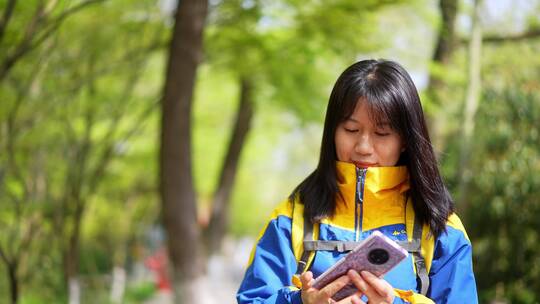 年轻阳光活力女孩春天户外踏青游玩刷手机