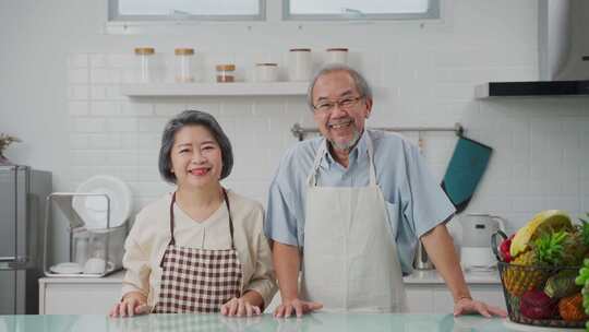 亚洲老年夫妇的肖像幸福地站在厨房里，微笑