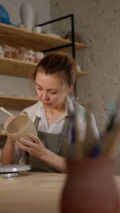 专注的女性波特在陶艺工作室用前景工具回顾