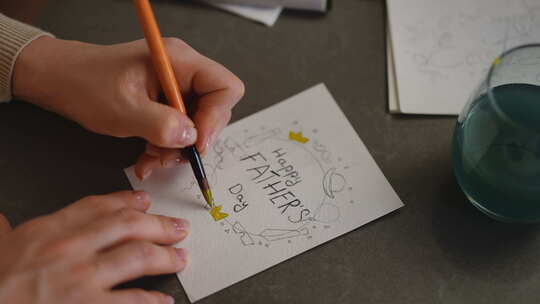 特写镜头一个女人用黄色水彩为父亲节画贺卡视频素材模板下载