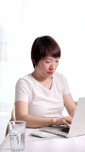 夏天使用笔记本电脑办公的东方年轻女性