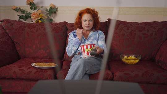 女人吃爆米花在家看电视视频素材模板下载