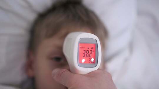 医生用非接触式温度计测量儿童体温
