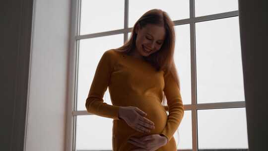 快乐的孕妇期待婴儿美丽多情的女母亲穿着橙