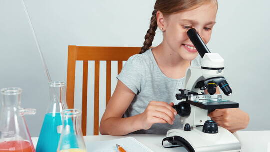 女孩使用显微镜观察实验视频素材模板下载