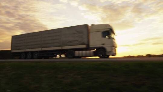 夕阳下在高速上运输货物的白色卡车
