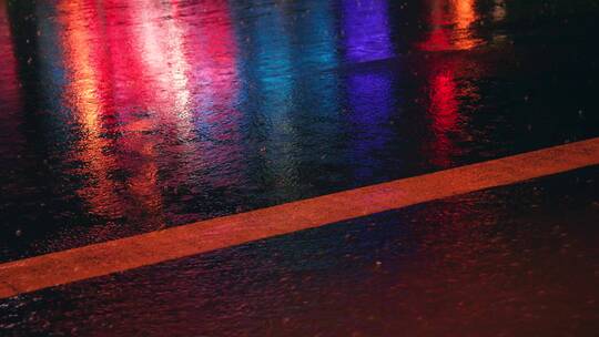 下雨天夜晚街道的雨水反射霓虹灯光