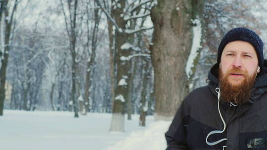男人戴耳机在冬天的公园里跑步