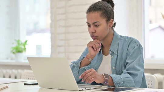 沉思的年轻非洲女人在笔记本电脑上工作，思考视频素材模板下载