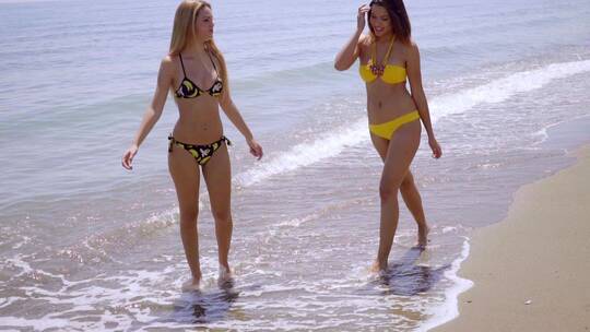 两个迷人的女人漫步在海滩上