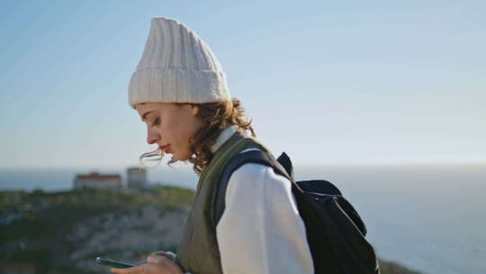 远足女孩在海洋山景发短信智能手机