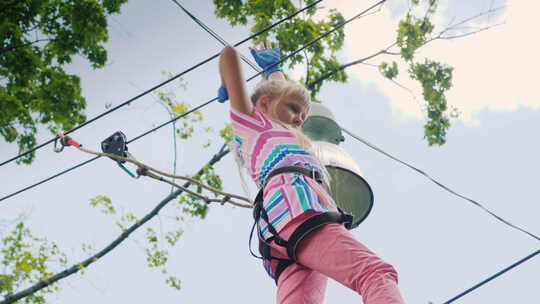 一个勇敢女孩的低天使视角沿着树之间的绳子视频素材模板下载