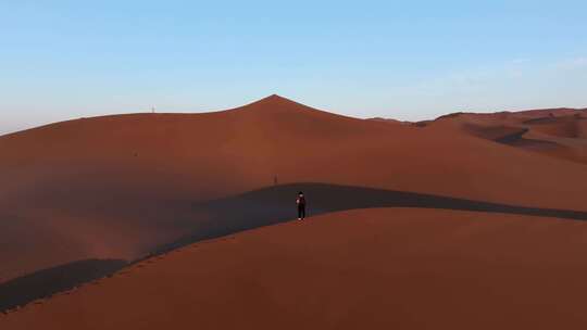 航拍男人行走在新疆库木塔格沙漠中