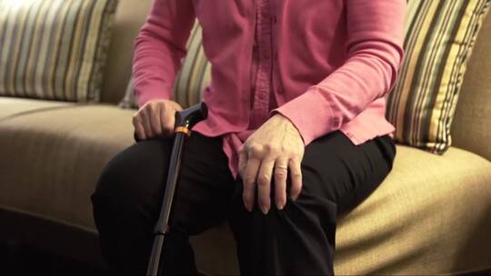 一个年长的女人痛苦地揉着她的膝盖4k