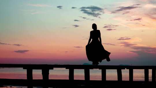 穿长裙的女子在海边日落时跳舞剪影视频素材模板下载
