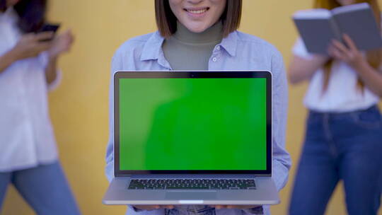 女人拿绿色屏幕的笔记本电脑