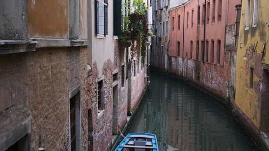 威尼斯狭窄的运河，贡多拉停在彩色房屋之间的水上